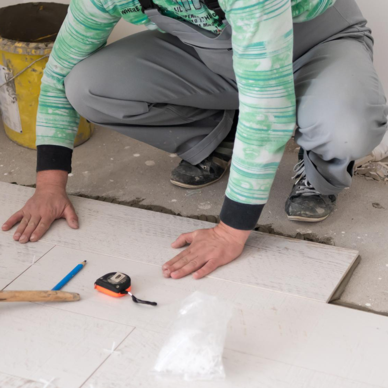 Floor tile installation in progress – technician laying wood-look tiles with precision tools