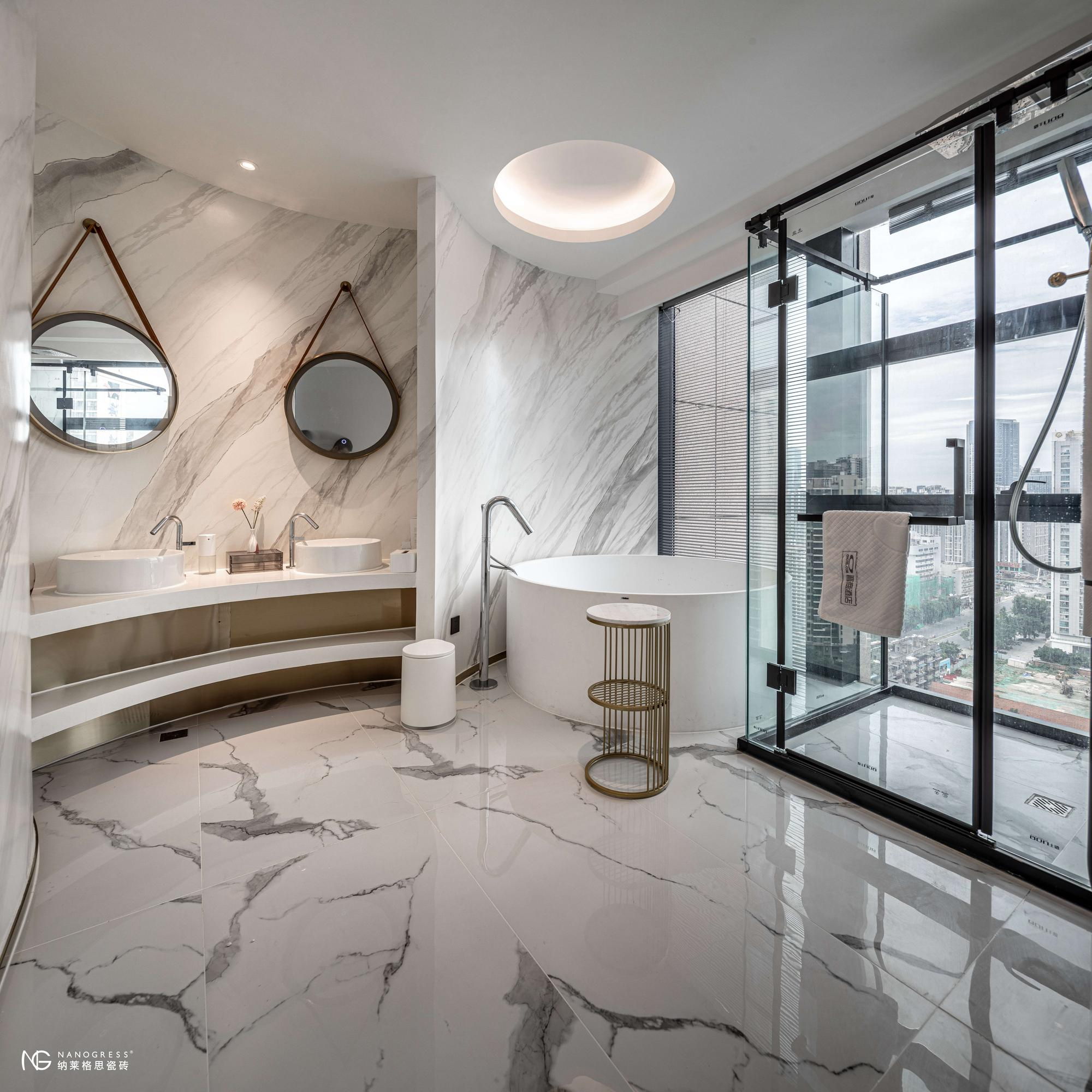 Bright contemporary bathroom with white marble walls, round mirrors, freestanding tub, and city view.