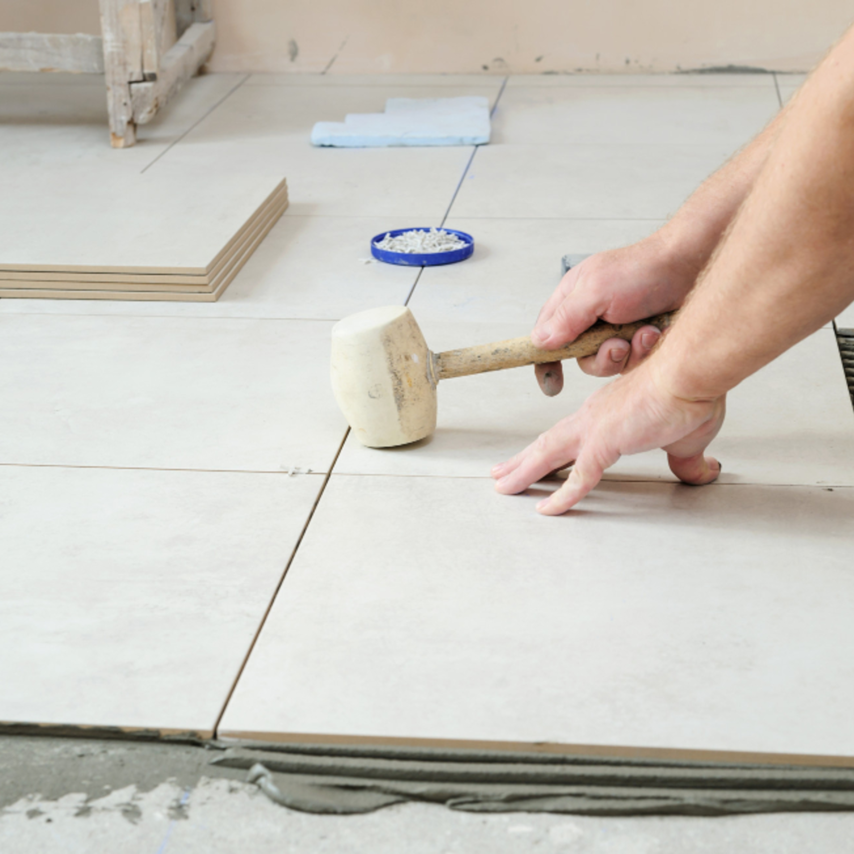 Tile installer leveling floor tiles with a rubber mallet during installation in Los Angeles